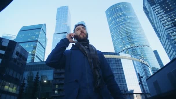 Manliga turist talar på sin telefon under promenader genom business complex. Röd episka film kamera film. — Stockvideo