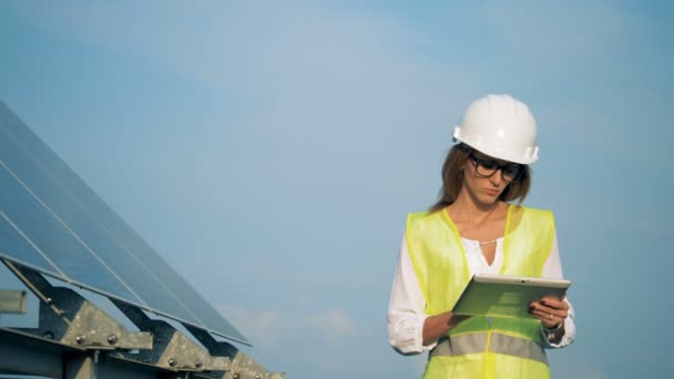 Trabalhadora está andando com um laptop em suas mãos e olhando para a instalação solar — Vídeo de Stock