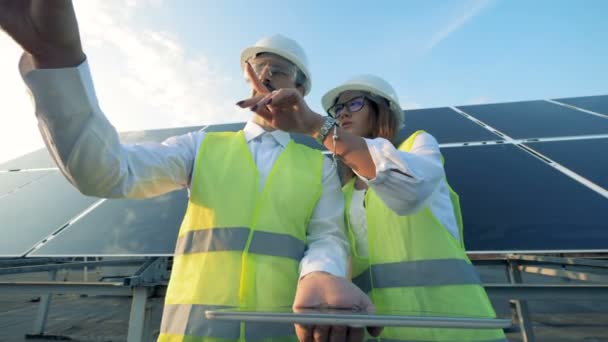 Técnicos estão discutindo a planta do projeto de construção perto de uma construção solar. Conceito de energia verde . — Vídeo de Stock
