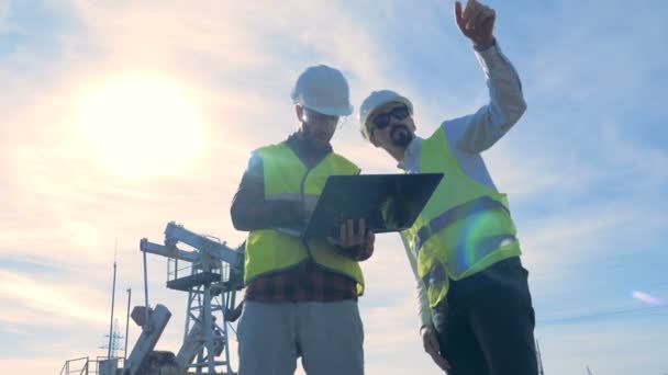 Working process of two male specialists in a petrol production site near oil rig, oil pump. — Stock Video