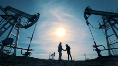 Erkek teknisyen el sıkışan ve petrol-derricks uzak birlikte yürüme