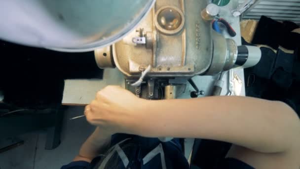 Un trabajador de la fábrica utiliza la máquina de coser en una mesa, vista superior . — Vídeos de Stock