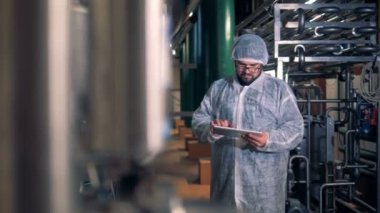 Bir erkekte iş giysisi onun tablet bir damıtım tesiste hesaplamalar yapma