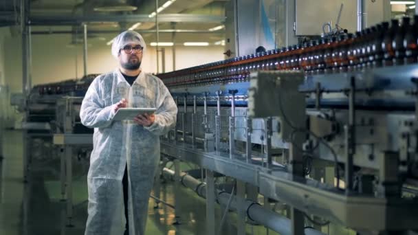 Brouwerij werknemer is het observeren van vervoer van bierflesjes langs de transportband — Stockvideo