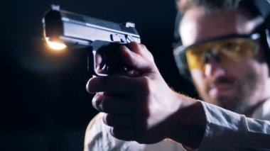 Erkek shooter çekim bir odada bir silah tutan, yakın çekim.