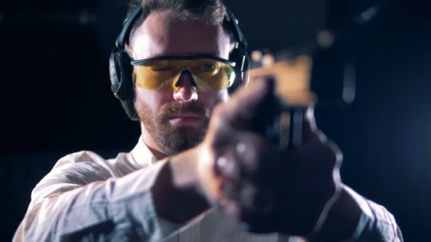 Persona en gafas apunta con un arma en un campo de tiro, de cerca . — Vídeo de stock