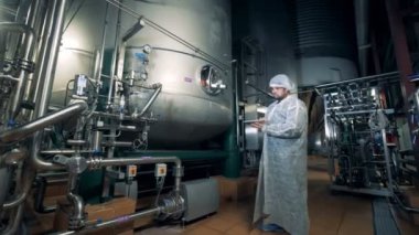 Bira fabrikası işçisi bira tanklarla denetler, yakın çekim.