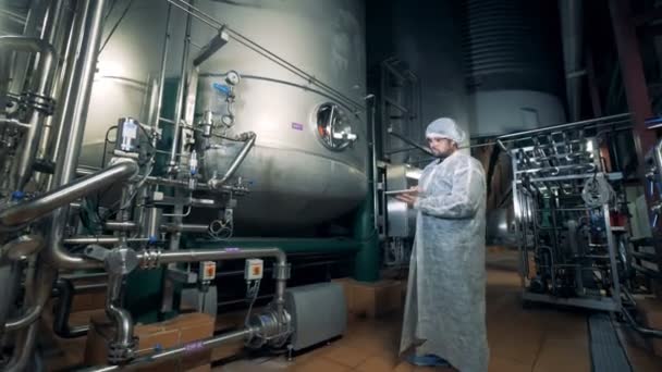 Brouwerij werkprocessen controleert tanks met bier, close-up. — Stockvideo