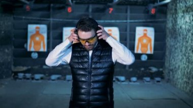 Kapalı kulaklıklar ve kamera çekim bir odada gülümser bir kişi koyar, yakın çekim.