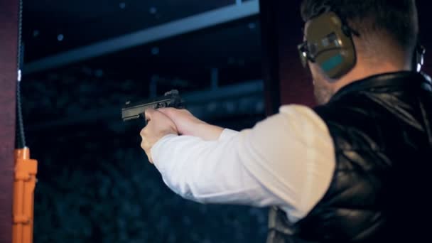 Una persona dispara un arma mientras entrena, mira hacia atrás . — Vídeos de Stock