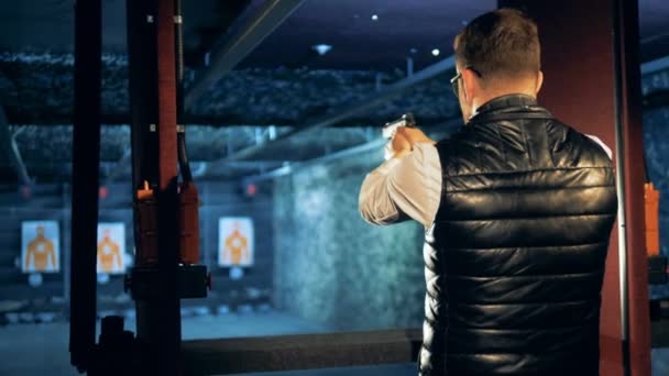 Male shooter aiming with a gun at a shooting range, back view. — Stock Video