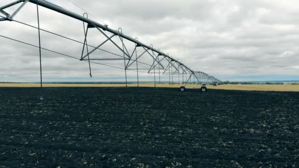 Campo agrícola com um mecanismo de irrigação montado nele — Vídeo de Stock