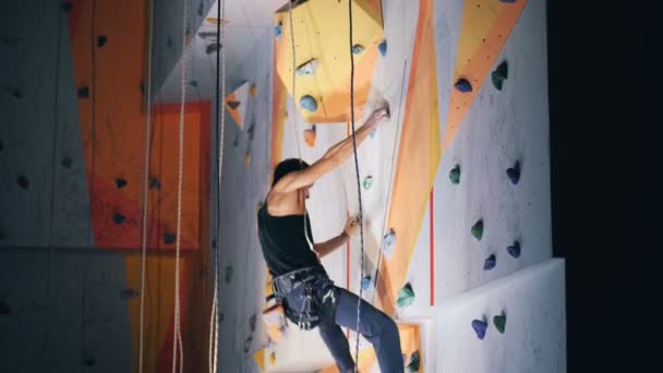 Een sportman stappen op een muur tijdens het klimmen, zijkant uitzicht. — Stockvideo