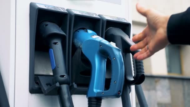 男性の手は、electrocar を充電する電気の給油ノズルを抜く — ストック動画