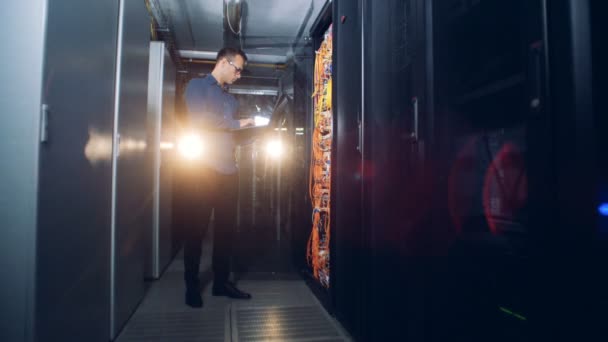Spécialiste de l'informatique se tient avec un ordinateur portable dans une salle de serveurs, gros plan .