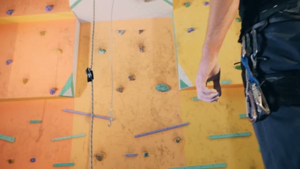 Homem alpinista fica perto de uma parede de escalada, de perto . — Vídeo de Stock