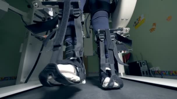 Las piernas de una persona con discapacidad física atada con cinturones se mueven a lo largo de la pista de senderismo — Vídeo de stock
