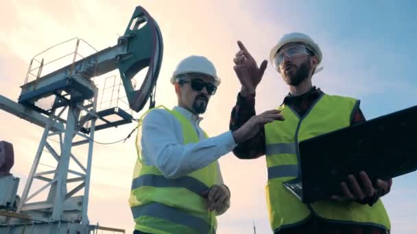 Werknemers in uniforme controle olie torens op een veld, close-up. — Stockvideo