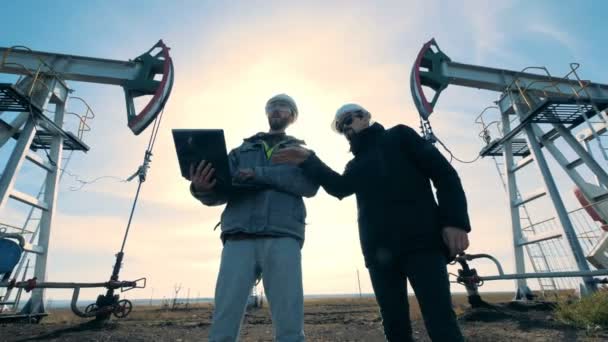 Zaměstnanci se o projektu, stojící poblíž ropné věže, pohled zespodu. — Stock video