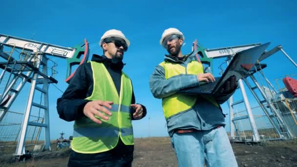 Menschen arbeiten mit einem Laptop auf einem Ölfeld, aus nächster Nähe. — Stockvideo