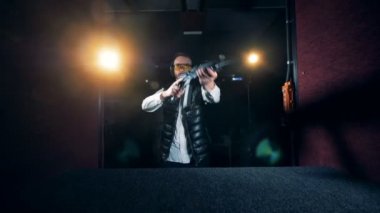 Donanımlı bir adam çekim bir odada tüfek hedefliyor. 4k