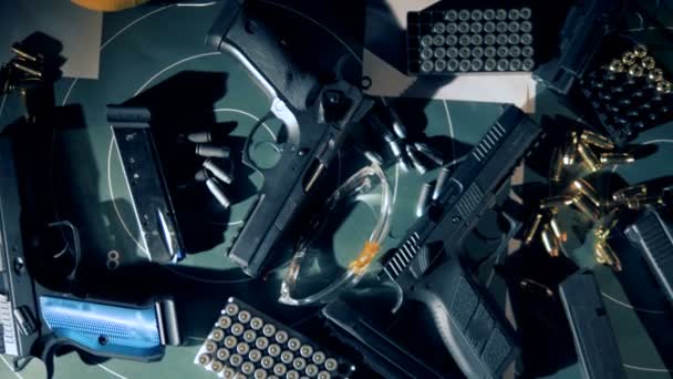 Armas, balas, fones de ouvido e óculos de proteção para fotografar em uma vista superior — Vídeo de Stock