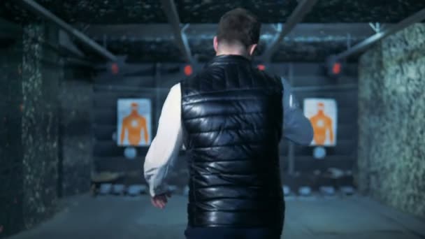Backside view of a man walking towards target lists in a shooting gallery — Stock Video