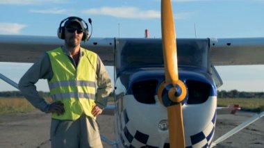 Pilot uçağa yakınındaki Tekdüzen standları. Özel kulaklık seti giyen erkek havacı bir kameraya benziyor.
