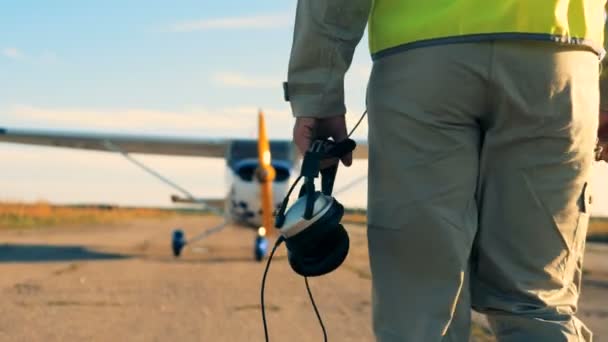 Αρσενικό pilot περπάτημα με τα ακουστικά στα χέρια, ΠΙΣΩ ΟΨΗ. — Αρχείο Βίντεο