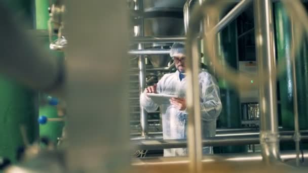 Инженер-мужчина управляет планшетом, стоя на пивоваренном заводе — стоковое видео