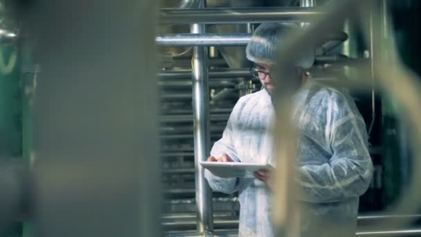 Installation de distillerie avec un technicien masculin observant et travaillant avec une tablette — Video