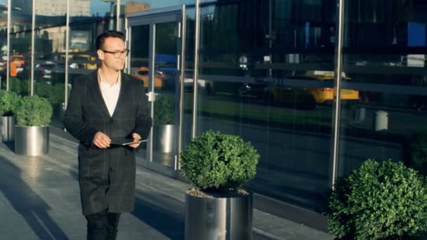 Περπατάει ένας επιχειρηματίας, κρατώντας ένα δισκίο, εσωτερικη. — Αρχείο Βίντεο