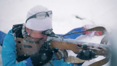 Bir kadın biatloncu çekerken kar düşüyor
