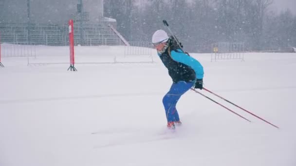 Ryssland, 05 mars 2018, skidskytte utbildningsprocessen. Idrottskvinna passerar snöig stadion i mitten av en skidskytte praxis — Stockvideo