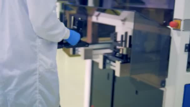 Um trabalhador de laboratório está colocando um equipamento de módulo solar em uma máquina transportadora em um chão de fábrica moderno . — Vídeo de Stock