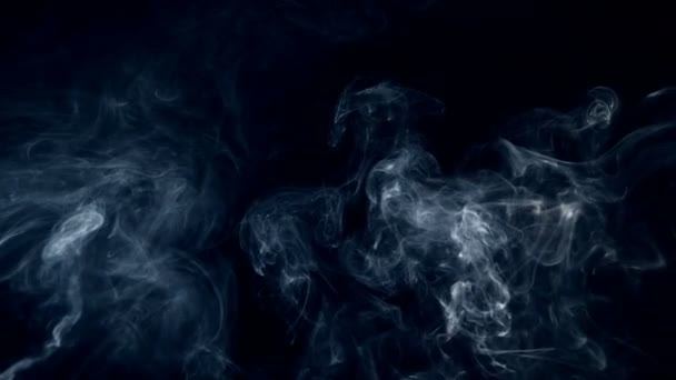 Puffs of fog, smoke, white abstract clouds are slowly swirling against the dark background — Stock Video