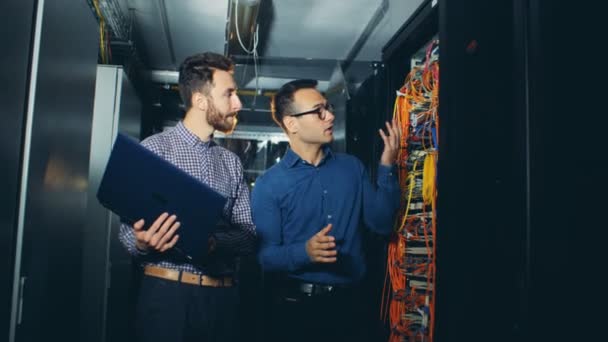 Técnico masculino en una sala de servidores está recibiendo instrucciones de su colega — Vídeos de Stock