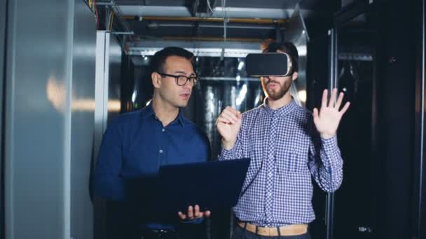 Een man gaat in virtual reality bril onder begeleiding van zijn collega — Stockvideo