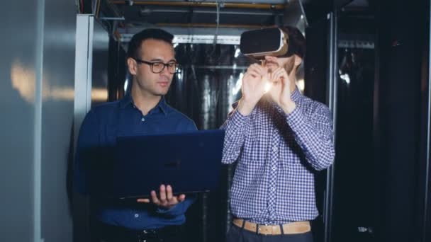 Инженер-мужчина контролирует опыт своих коллег в виртуальных очках с компьютера — стоковое видео