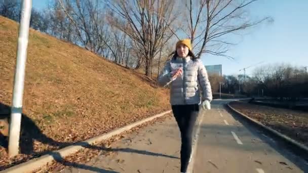 Νεαρή κοπέλα με ένα ρομποτικό βραχίονα τρέχει κατά μήκος του πάρκου. — Αρχείο Βίντεο