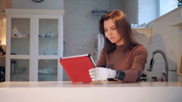 Een dame met een robotachtig wapen functioneert een tablet — Stockvideo