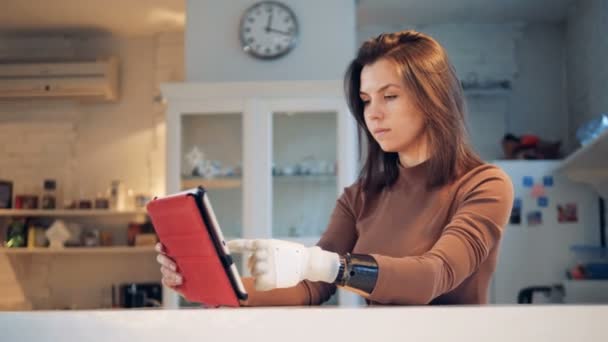 Планшетным компьютером управляет девушка с протезной рукой — стоковое видео