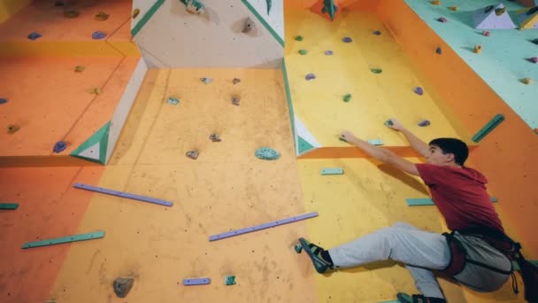 Un hombre está saltando de una sección de un muro de escalada a otra — Vídeos de Stock