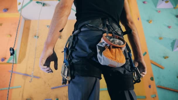Homem equipado estar pronto para começar a clambering uma parede de ginásio em uma visão traseira — Vídeo de Stock