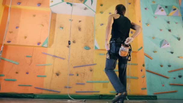 Een man is poederen van zijn handen en aanstalten om een sportschool muur klauteren — Stockvideo