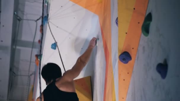 Vista lateral de una pared de cantos rodados y un hombre equipado escalando a lo largo de ella — Vídeos de Stock