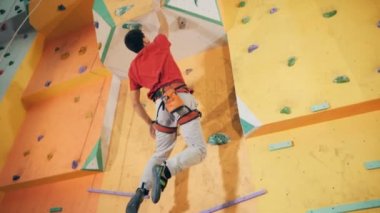 Erkek tırmanma atlama ve bouldering duvarda asılı. 4k