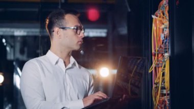 Bir veri merkezinde duran bir dizüstü bilgisayar ile kişinin çalıştığı.