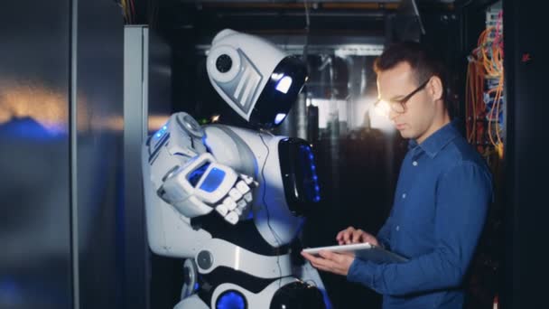 Il programmatore controlla un robot in una stanza server, da vicino . — Video Stock