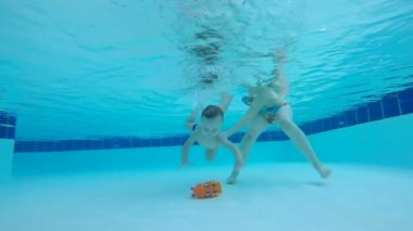 Bir havuzda dalış öğrenen bir bebek. Sualtı yüzme yürümeye başlayan çocuk.